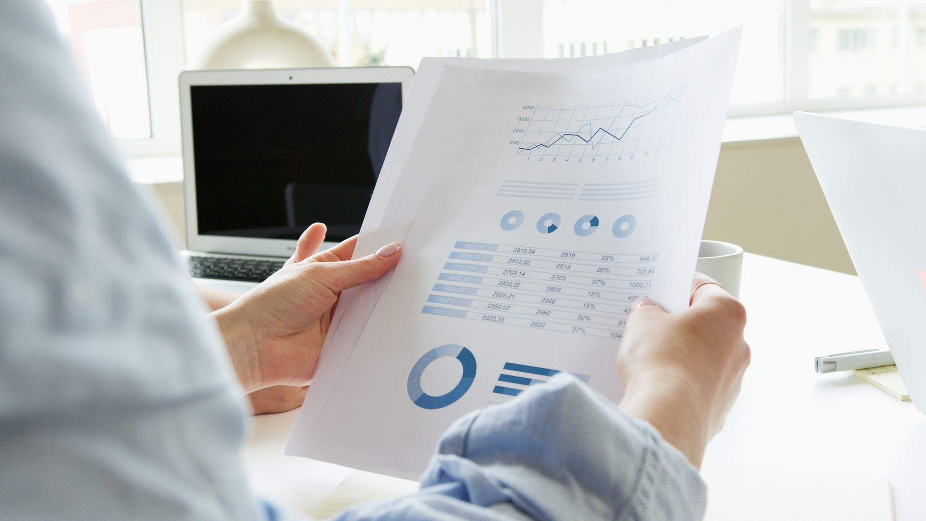 A person reviewing printed business charts and graphs at a desk