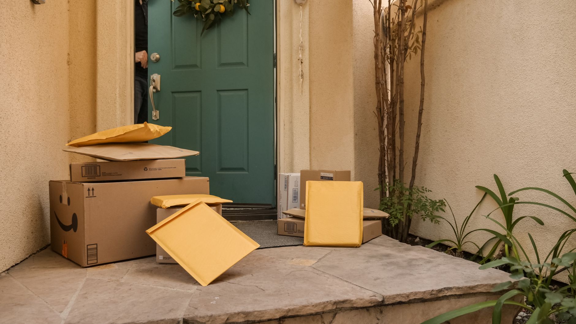 Delivery boxes and padded mailers stacked at a front door