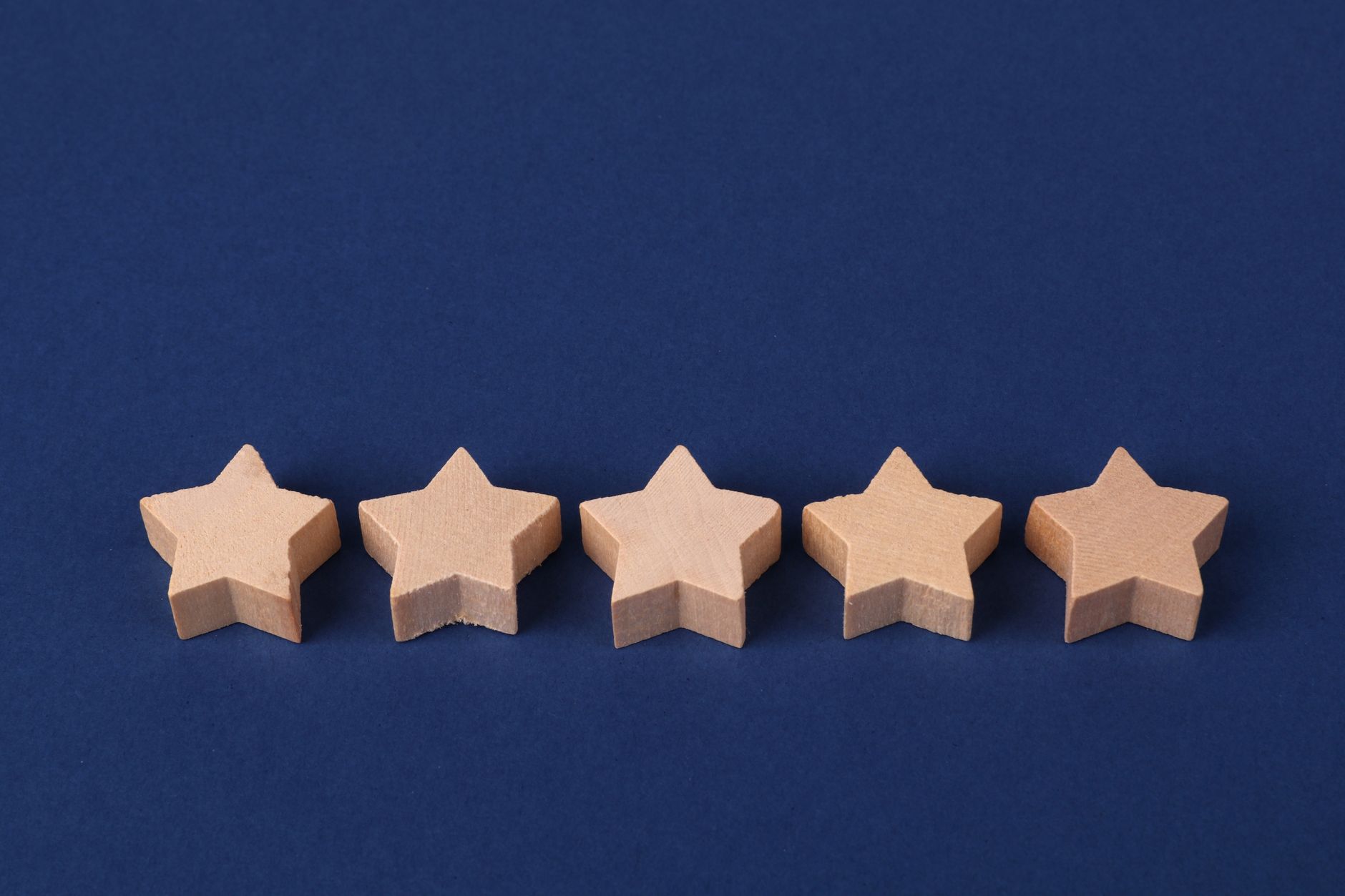 Five wooden stars in a row on a navy blue background