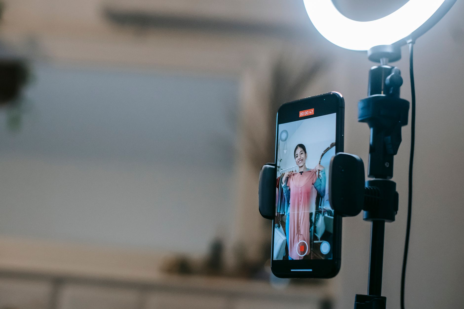 A phone on a ring light stand recording a vertical video of a woman
