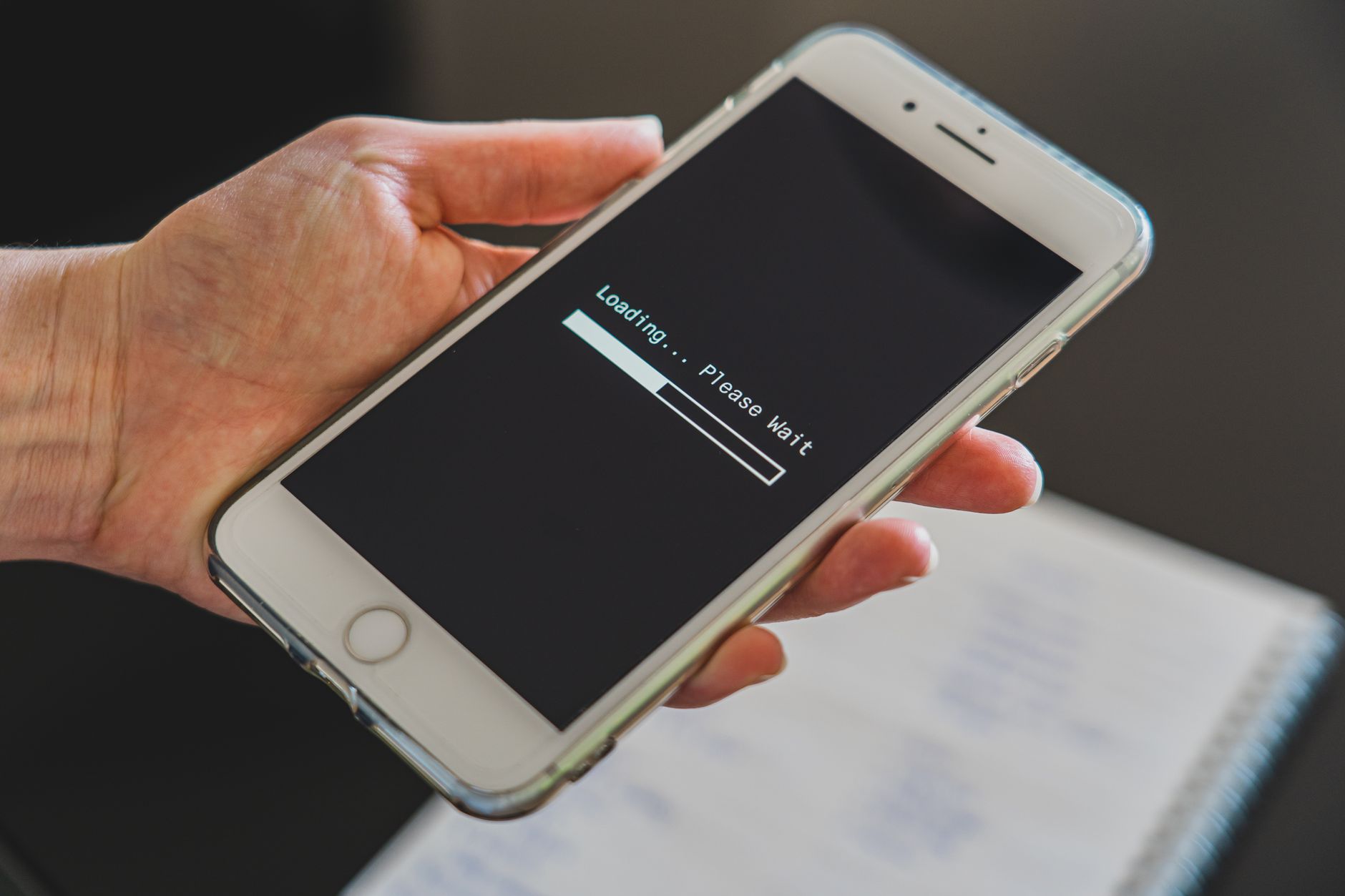 A hand holding a smartphone that shows a loading screen