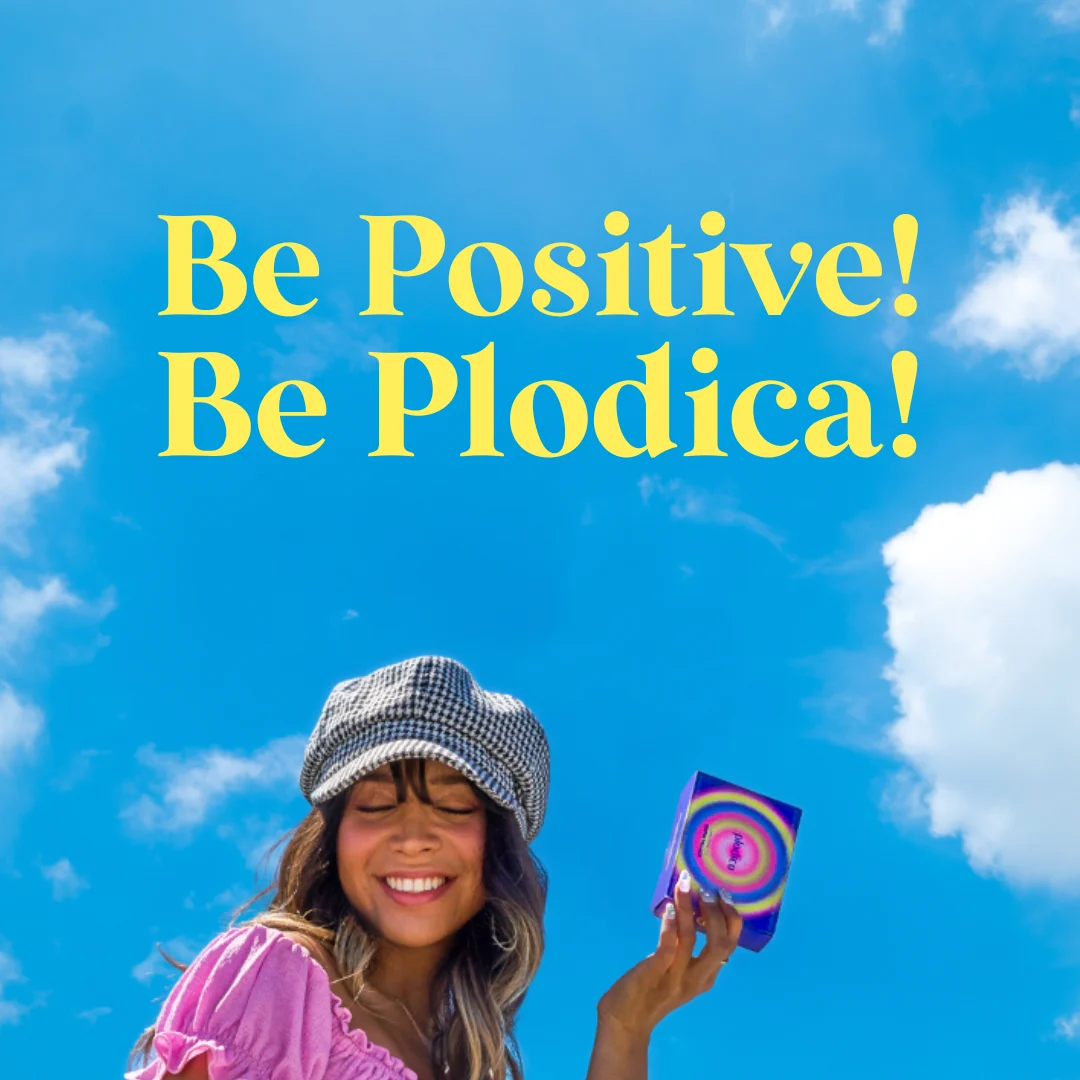 Be Positive! Be Plodica! launch graphic, a smiling woman holding the tie-dye Plodica box against a blue sky